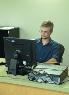 Matthew Stoddard, full time employee of the University of Idaho ITS help desk works at his computer Thursday in the basement of the Student Union Building.