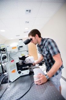 Philip Vukelich | Argonaut John Nuhn, senior, focuses a confocal microscope on a slide of mouse eye cells. Nuhn's summer research on mouse retinas was funded by the Idaho INBRE program.