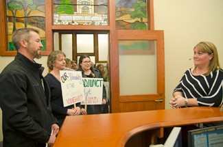 Nathan Romans | Argonaut English Department Lecturer Jeff Jones hands a protest poster to CLASS Assistant to the Dean Jennie Hall after the contingent faculty marched from the Commons Rotunda in protest of adjunct faculty rights at 2 p.m. Wednesday.