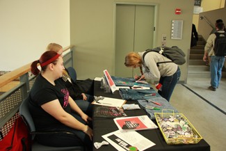 Yishan Chen | Argonaut Mimi Price (left) and Katie Estey watch as Zoe Marko signs a pair of jeans while they table to raise awareness of Denim Day Wednesday in the Commons.